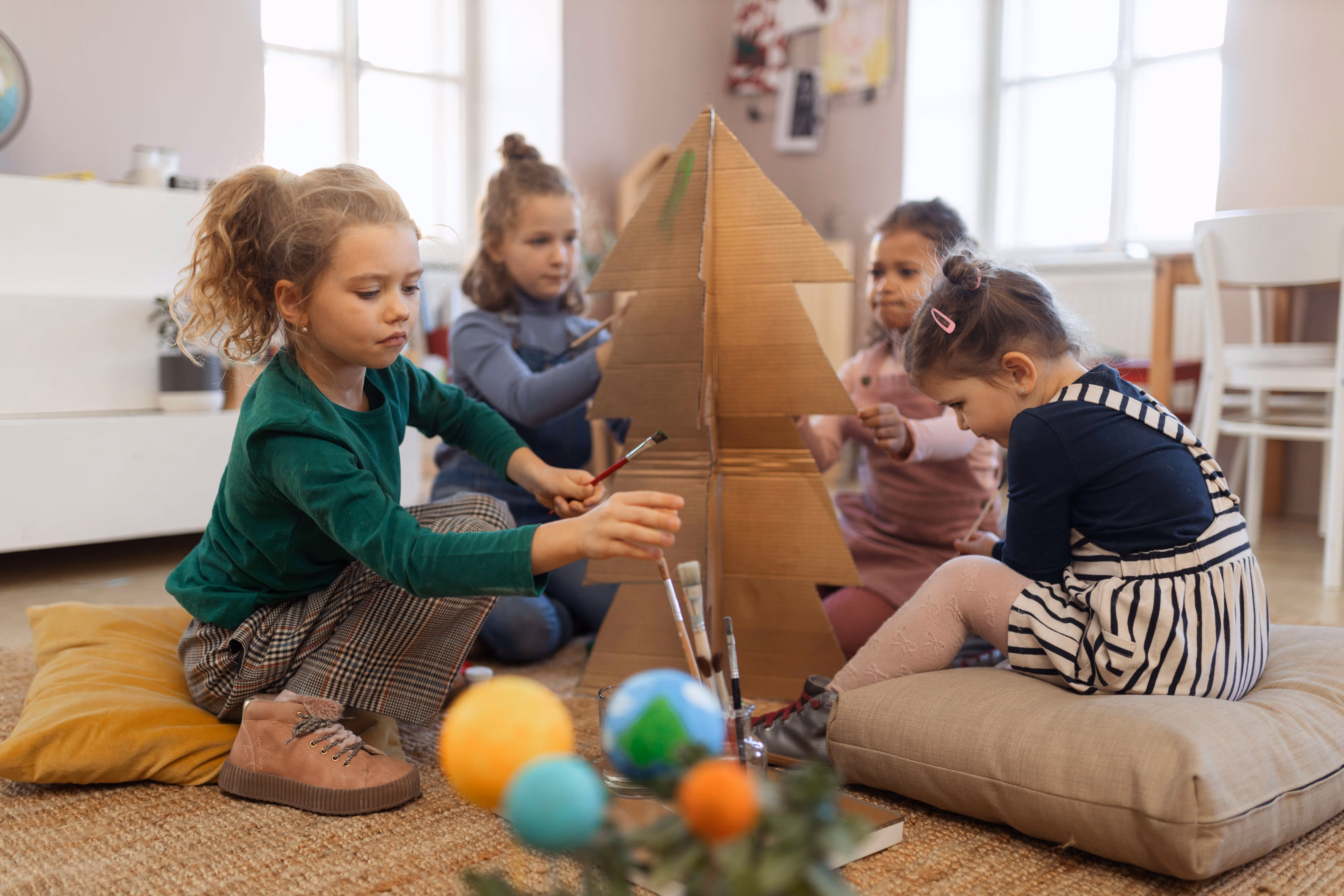 4 kids playing with cardboard tree toy